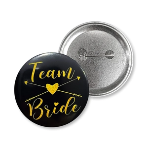 Detail view of Team Bride tinplate badge with gold glitter font and safety pin back
