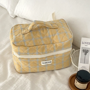 Detailed close-up of yellow plaid quilted cosmetic bag with soft cotton texture and handle
