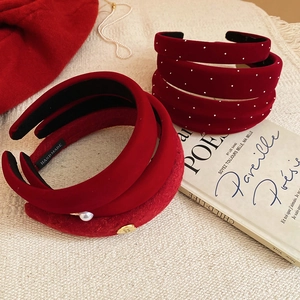 Detail of red velvet headbands with pearl accents and handmade label on beige fabric