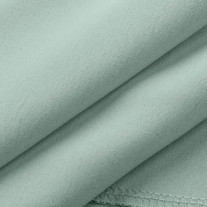 Primer plano de tela de gasa verde claro con textura fina y detalles de dobladillo