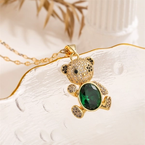 Detail of a gold bear pendant with a green oval gemstone and clear zircon pavé accents