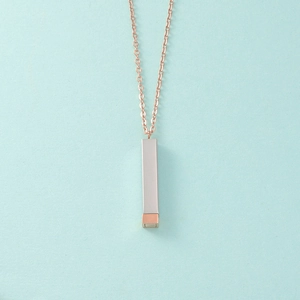 Détail chaîne or rose avec pendentif cylindrique bicolore argent et or rose