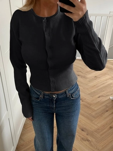Gros plan d'un cardigan noir en maille avec poignets côtelés et boutonnage simple