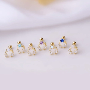 Set of 7 gold titanium steel helix studs with colorful zircon stones on white fabric