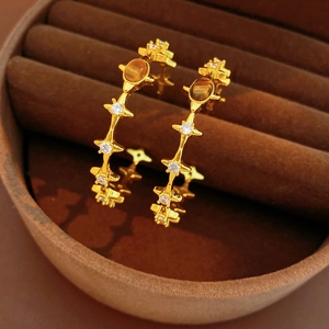 Macro view of gold-plated hoop earrings featuring tiger eye stones and zircon stars