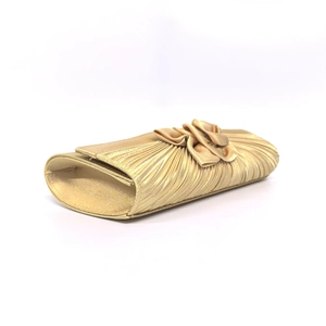 Close-up of pleated champagne satin fabric and 3D floral decoration on the evening clutch