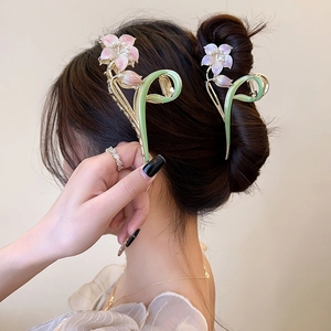 Detail of floral alloy hair claw clips with colorful enamel petals and pearl centers