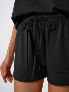 Detail of black knit shorts with adjustable drawstring elastic waist and dual patch pockets
