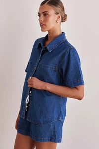 Detail view of washed dark blue denim texture on women's short sleeve shirt and shorts set