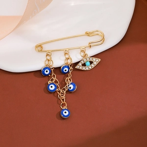 Detail of gold tassel brooch with blue evil eye charms, turquoise bead and sparkling crystals