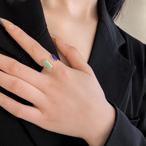 Detail of vintage French gold open ring with green and blue enamel on a female hand