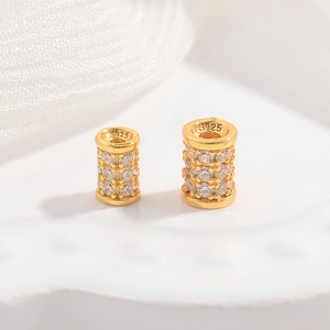 Macro shot of 925 sterling silver cylinder charms with sparkling cubic zirconia in gold