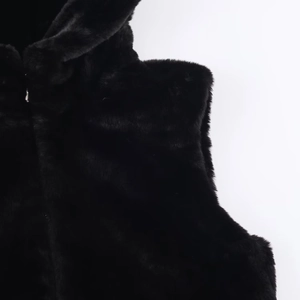 Detailaufnahme der flauschigen schwarzen Kunstpelz-Textur einer Weste mit weichen Fasern