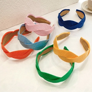 Colorful handmade braided raffia headbands set in pink, blue, and yellow on white background