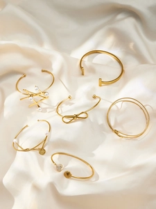 Close-up of six minimalist 18k gold plated bracelets with pearls and lucky charms