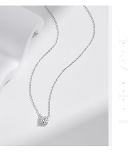Macro shot of a silver moissanite pendant necklace on a white pedestal with Good Luck text