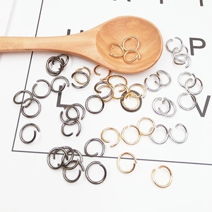 Detailed close-up of mixed metal jump rings in a wooden spoon for DIY jewelry crafts