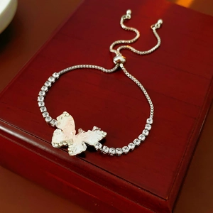 Détail macro du bracelet papillon avec texture nacre rose sur boîte à bijoux