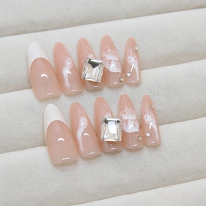 Long almond press-on nails in sheer pink with white French tips and luxury rhinestones
