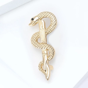 Macro view of gold snake and caduceus brooch with black gemstone eyes for suits