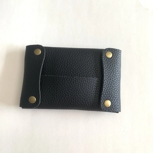 Close-up of black litchi pattern leather mini pouch with four brass snap buttons