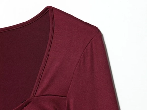 Detaillierte Nahaufnahme von quadratischem Ausschnitt und Schulternaht der burgunderroten Strickjacke