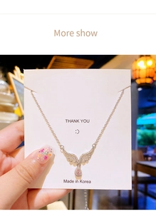 Close-up of angel wing necklace with pink water drop zircon pendant on display card