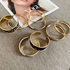 Detail of four-piece gold bracelet set with leopard print leather inlays on stone surface