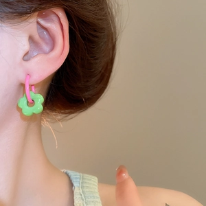 Detail of pink and green floral hoop earrings worn by a model in a summer style close-up