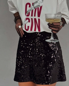 Détail du T-shirt blanc imprimé 'CIN CIN' et jupe noire à paillettes pour un look de fête