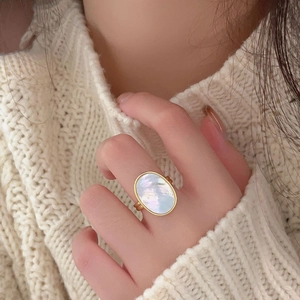 Detail of 925 sterling silver gold oval ring with iridescent shell on knit sweater