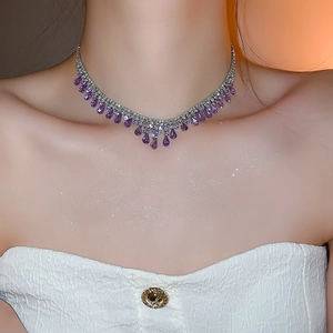 Close-up of elegant silver necklace with purple teardrop gemstones on model's neck