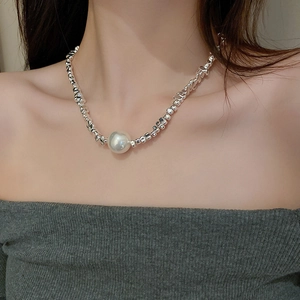 Close-up of irregular silver beads necklace with a large pearl pendant on a model's neck