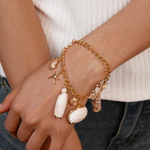Close-up of beach-style golden bracelet with starfish, seashell, and conch pendants
