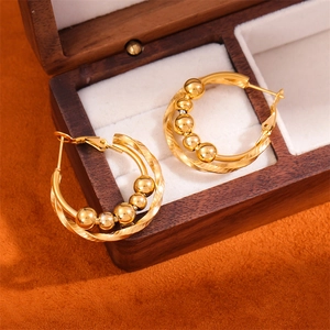 Close-up of gold stainless steel twisted hoop earrings with five beads on white velvet