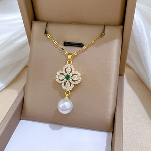 Macro shot of gold necklace featuring green gemstone, zircon pavé, and large pearl drop