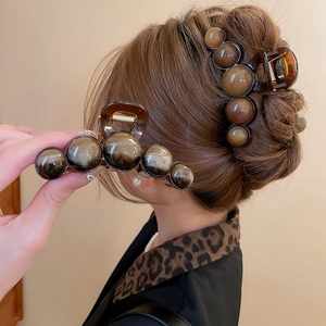 Detail of a large amber tortoiseshell hair claw clip with geometric marble pattern beads