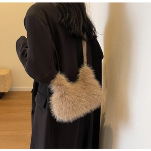 Detailed close-up of brown faux fur shoulder bag with leather strap on black coat