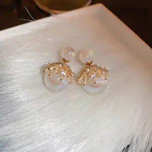 Elegant gold plated pearl earrings with sparkling zircons on soft white velvet background