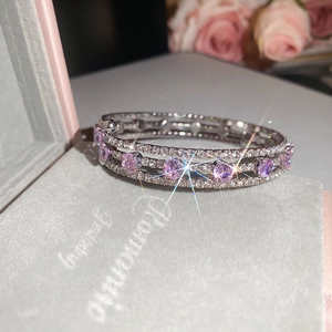Macro detail of triple-layer silver bracelet with pink zircons on velvet jewelry box