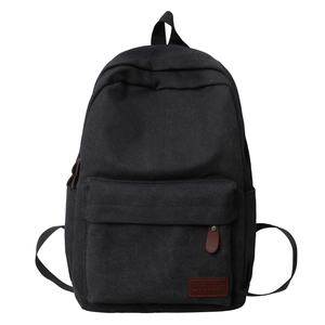 Front view of minimalist black canvas backpack with leather logo tag for daily use