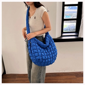 Quilted blue cloud tote bag with textured ruffles and shoulder strap shown on model
