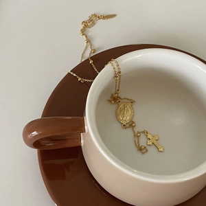 Vintage gold 925 silver necklace with Virgin Mary medal and cross on a coffee cup