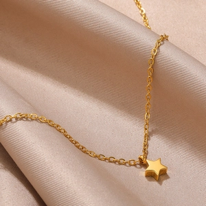 Polished gold star pendant on a delicate chain over champagne silk background