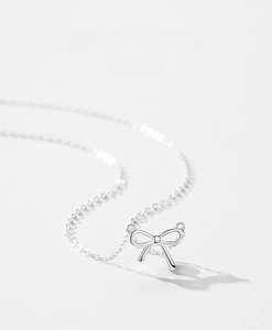 Vue macro du délicat pendentif nœud en argent S925 sur un collier élégant à chaîne fine
