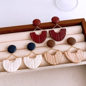 Detail view of U-shaped leather resin drop earrings in red, blue and brown variants