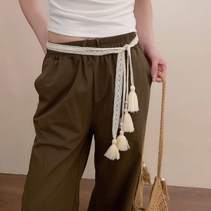 Detail of cream lace fringe belt styled with olive green linen trousers for a resort look