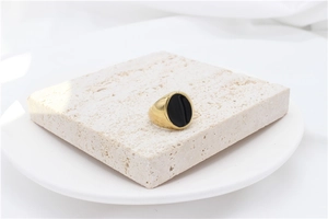 Minimalist gold signet ring with oval black enamel inlay displayed on stone