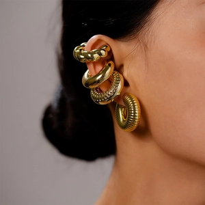 Detailed close-up of four gold metallic ear cuffs with twisted and ribbed textures