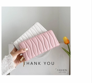 Detail of pink and white wave-quilted PU leather long wallets with golden zippers